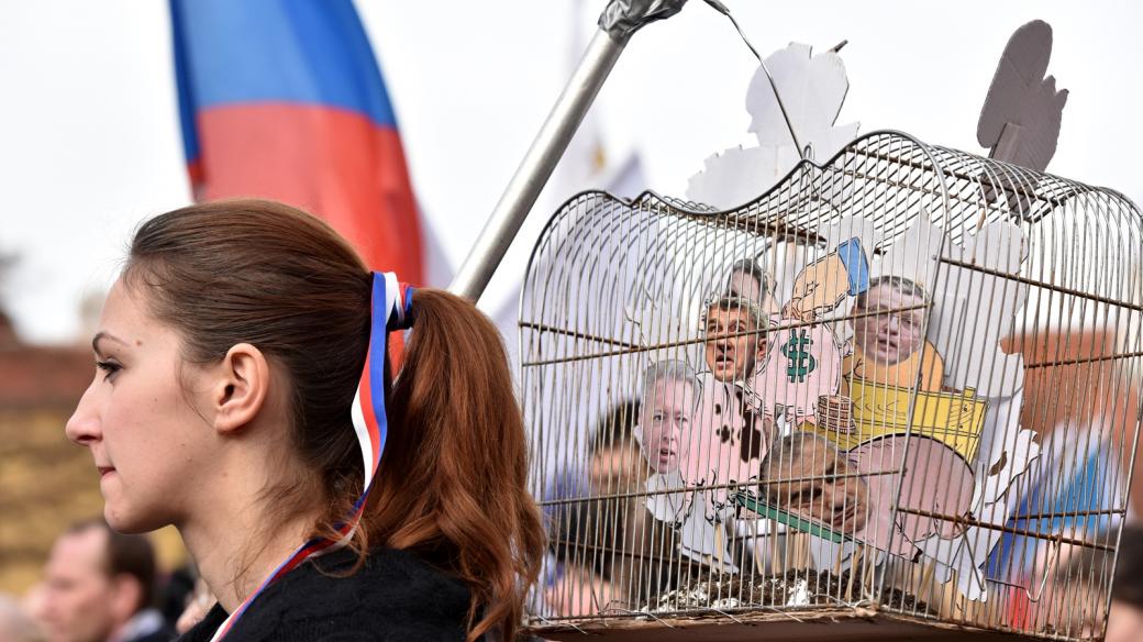 Na Loretánském náměstí mají demonstranté české trikolóry, vlajky, protestní nápisy i rekvizity