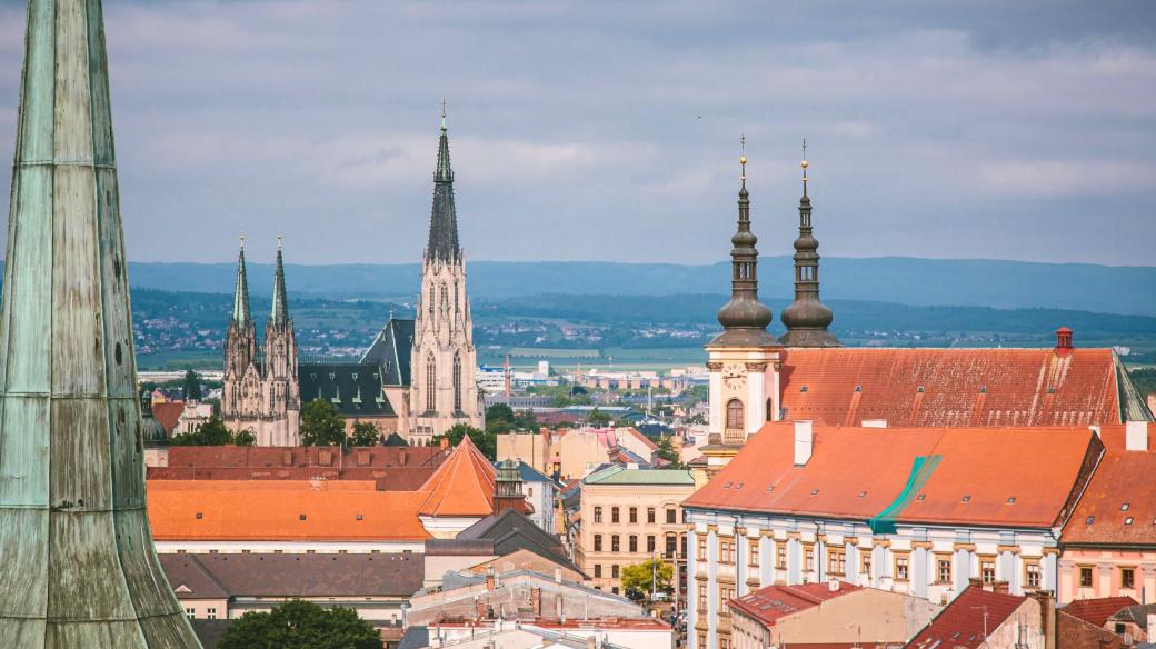 Věže olomouckých kostelů. Vlevo věž nad hlavní lodí Chrámu sv. Mořice, uprostřed vzadu Katedrála sv. Václava a vpravo dvojice věží Kostela Panny Marie Sněžné na Náměstí Republiky