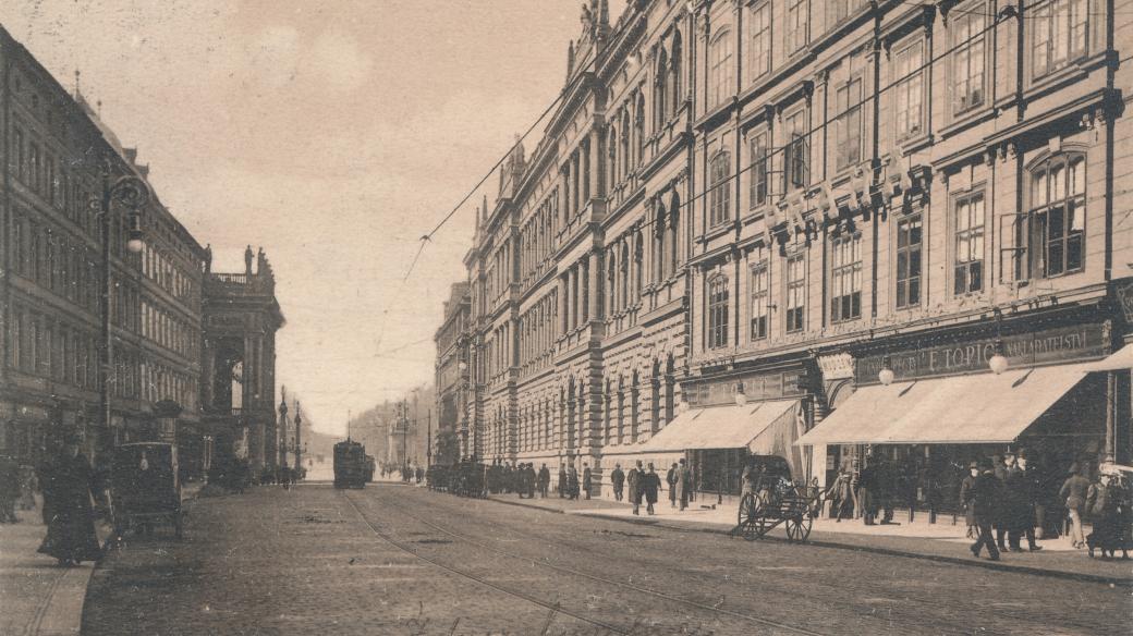 Ferdninadova třída, dnes Národní, směrem k mostu císaře Františka. Vlevo Národní divadlo.Zprava je dům čp. 1011, ještě ve své klasicistní podobě před secesní přestavbou. V přízemí vidíme knihkupectví F. Topiče