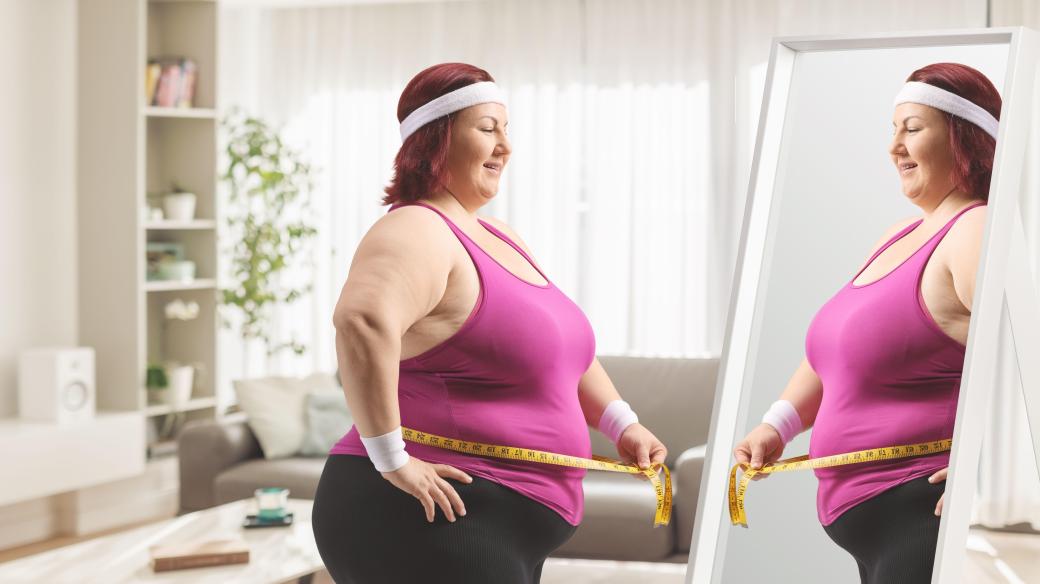 Žena s nadváhou se prohlíží v zrcadle