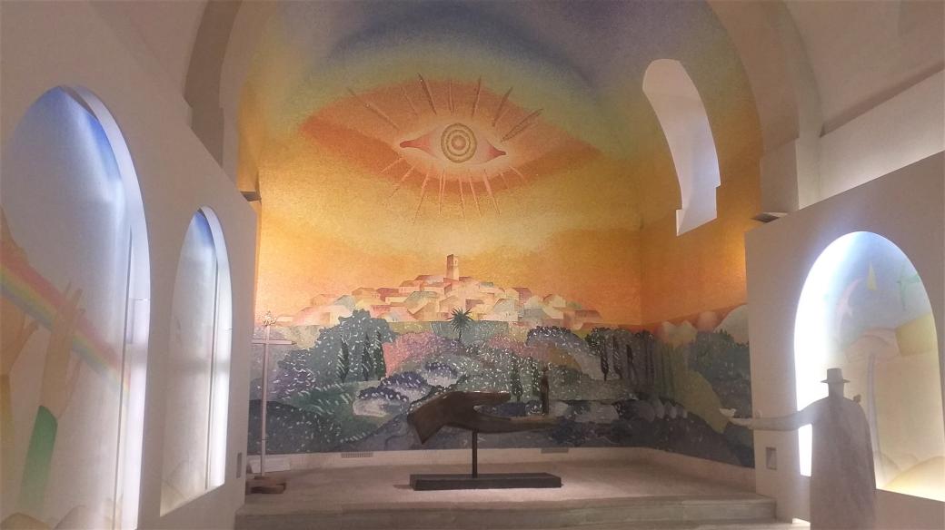 Jean-Michel Folon: kaple ve vesnici Saint-Paul de Vence, jižní Francie. Monumentální mozaika s panoramamtem vesnice Saint-Paul de Vence, na níž dohlíží oko – jako symbol ochrany i věčně svítícího středomořského slunce
