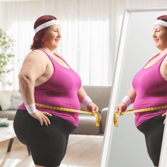 Žena s nadváhou se prohlíží v zrcadle