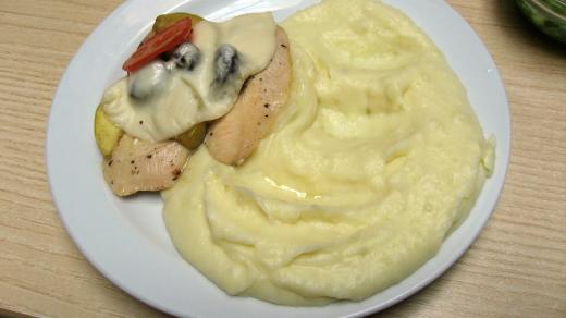 Kuřecí plátek, pokrytý sýrem, jablkem, švestkama a rajčetem s bramborovou kaší.