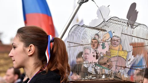Na Loretánském náměstí mají demonstranté české trikolóry, vlajky, protestní nápisy i rekvizity