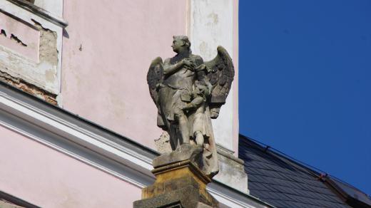Socha anděla strážného na přední stěně kostelního portálu