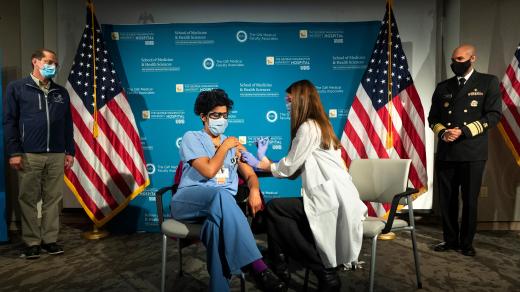 první očkování ve Spojených státech (Health and Human Services Secretary Alex Azar, at left, and US Surgeon General Dr. Jerome Adams, far right, watch as Dr. Sheetal Sheth, center left, OB-GYN and Medical Director for Labor and Delivery)