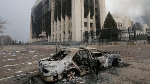 Shořelé auto před budovou radnice v kazašském Almaty, která byla během protestů zapálena