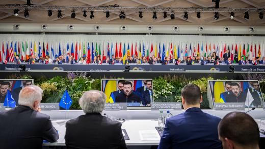 Ukrajinský prezident Volodymyr Zelenskyj na monitorech při své účasti na plenárním zasedání summitu