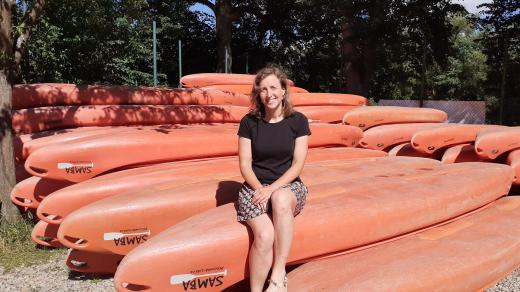 Paní Anna Holubová u kánoí své půjčovny lodí Samba.Kánoe mají typickou tmavě oranžovou barvu
