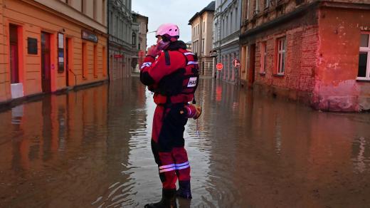 Hasič, záchranář v zatopené ulici poblíž rozvodněné řeky Opavy