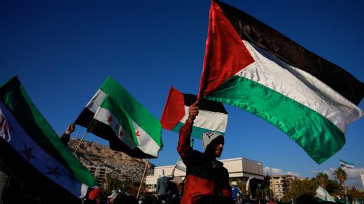 Lidé mávají palestinskou vlajkou a vlajkou přijatou novými syrskými vládci, jak lidé oslavují poté, co bojovníci vládnoucího syrského orgánu svrhli syrského Bašára Asada, ve starém městě Damašku, Sýrie, 13. prosince 2024