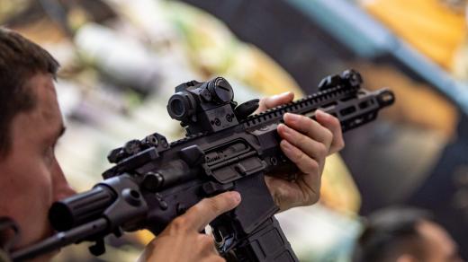 Návštěvník zkouší zbraň u stánku Colt CZ Group na mezinárodním bezpečnostním veletrhu v Brně (28. května 2025)