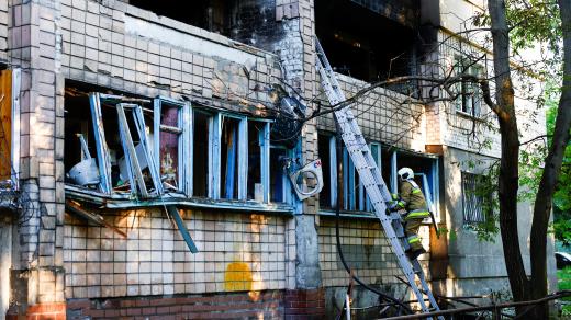 Hasič v bytovém domě poškozeném během ruských útoků dronů a raket na Kyjev, Ukrajina, 4. července 2025
