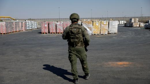 Izraelský voják stojí vedle balíků s humanitární pomocí, které čekají na převoz z Izraele do Gazy