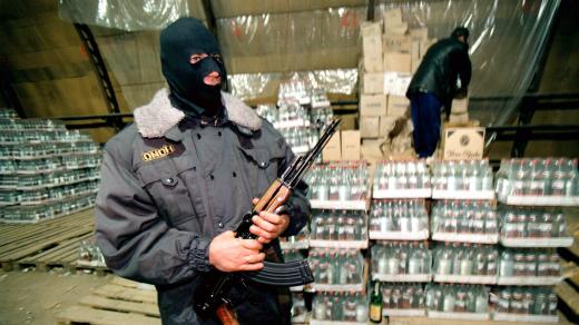 Příslušník zvláštní jednotky ruské policie hlídkuje u nelegálně vyrobené vodky (snímek z roku 1998)