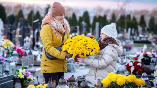 Lidé dávají na hroby květiny a svíčky