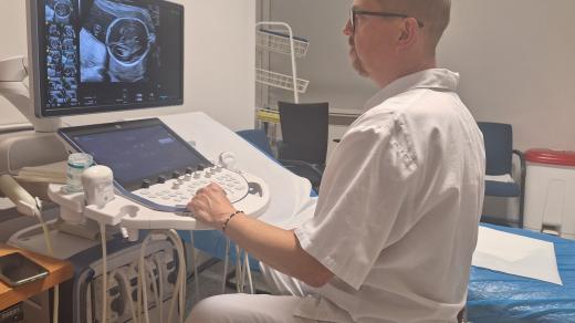 Sonografista Martin Hynek z porodnice U Apolináře s nasnímaným miminkem na obrazovce