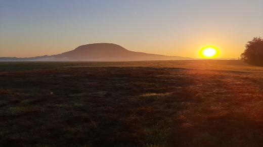 Východ slunce za horou Říp na dlouhé mohyle Vražkov, říjen 2021
