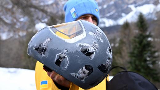 Ukrajinský skeletonista Vladyslav Heraskevyč ukazuje helmu s fotografiemi sportovců zabitých během ruské invaze