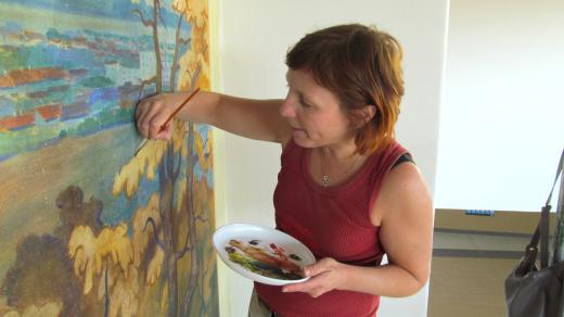 Hana Bělinová při obnovování Procházkových maleb na jičínském vlakovém nádraží v roce 2013