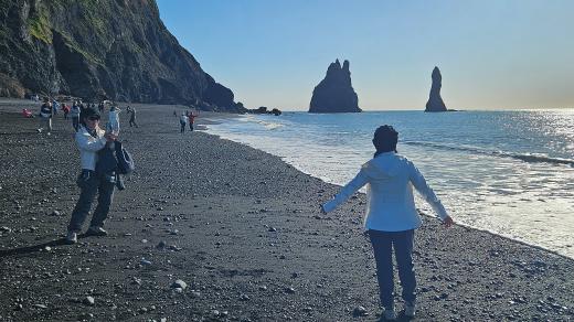 Černá pláž Reynisfjara se skalami v moři a turisty