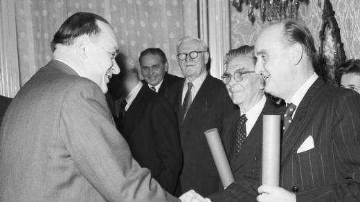 Ministr školství a kultury František Kahuda (vlevo) předává řediteli Státního divadla v Karlíně Juliu Léblovi (vpravo) a akademickému malíři Vilému Nowakovi (druhý zprava) dekret o jmenování zasloužilým umělcem