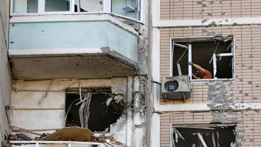 Lidé odstraňují rozbitá okna v poškozeném bytovém domě po útoku ukrajinského dronu v Krasnogorsku
