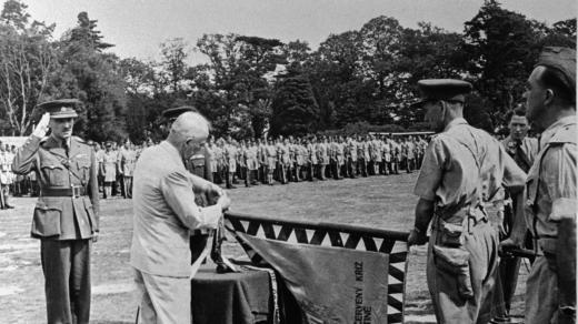 Prezident Edvard Beneš uděluje plukovnímu praporu insignie Čs. vojenského kříže. Vlajku věnoval oddílu Československý červený kříž v Palestině. Prapor drží plukovník Karel Klapálek