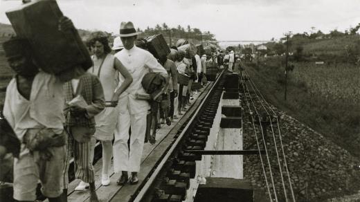 Turisté na Jávě kvůli poruše přecházejí přes železniční most (1920)