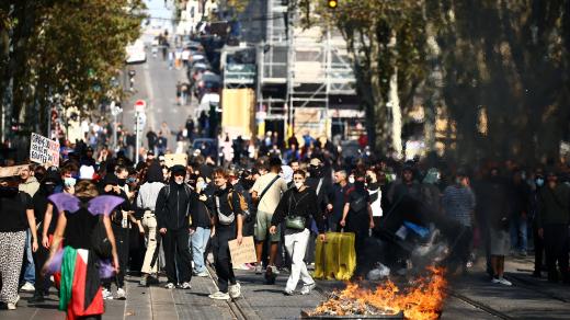 Protestující stojí poblíž hořících předmětů uprostřed střetů s francouzskou policií během demonstrace v Marseille