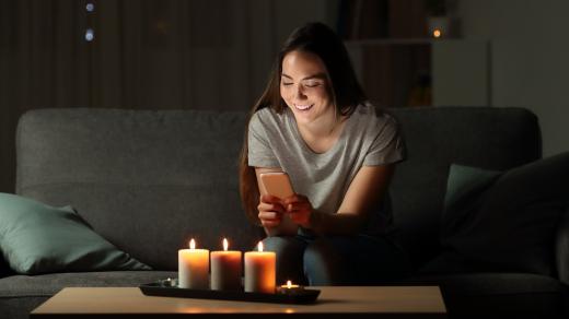 Žena píše zprávu na telefonu při svíčkách