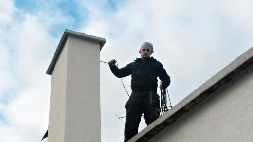 Kominík Jakub Kůta pracuje na střeše