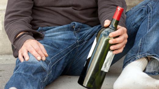 alkoholik (poor drunk man lying near trashcan in city street) 