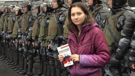 Activist Olga Misik holding a copy of the Constitution of the Russian Federation stands in front of riot policemen during a protest in Moscow on August 10, 2019