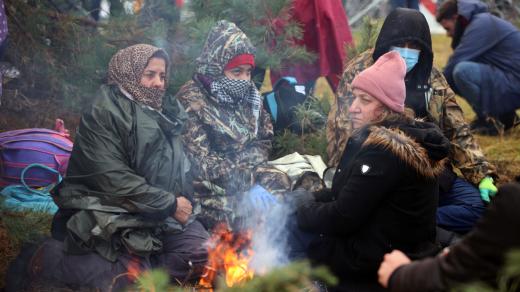 Skupina žen na bělorusko-polské hranici se snaží zahřát u ohně