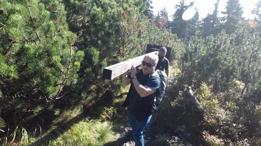 Aleš Spurný a Michal Ulrych nesou sloupek rozcestníku na Jelení studánku