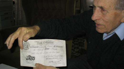 Adolf Burger ukazuje fotokopii jedné z padělaných bankovek