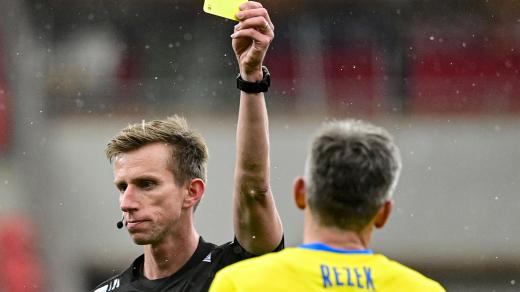 Fotbalový rozhodčí Jan Machálek dává žlutou kartu