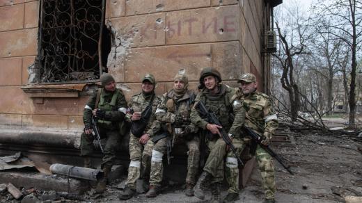 ruští vojáci odpočívají u zničené budovy v Mariupolu